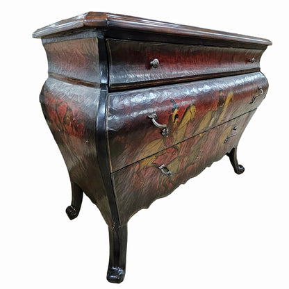 A vintage French-style chest of drawers with a dark reddish-brown and black distressed finish, featuring three drawers with ornate metal pulls and curved cabriole legs, isolated on a white background.