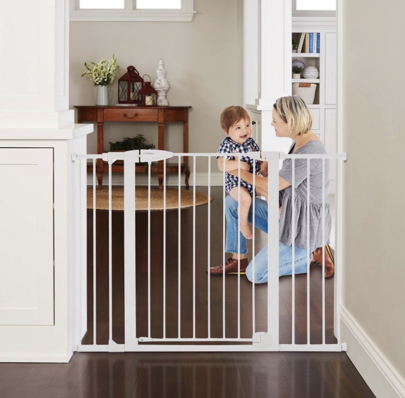 Woman and child behind a white baby gate in a home setting
