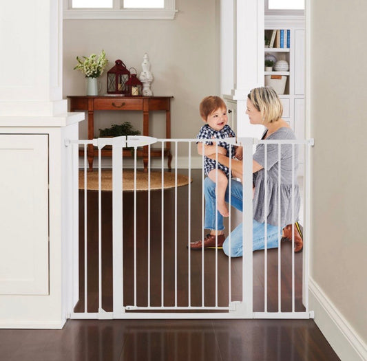 Woman and child behind a white baby gate in a home setting